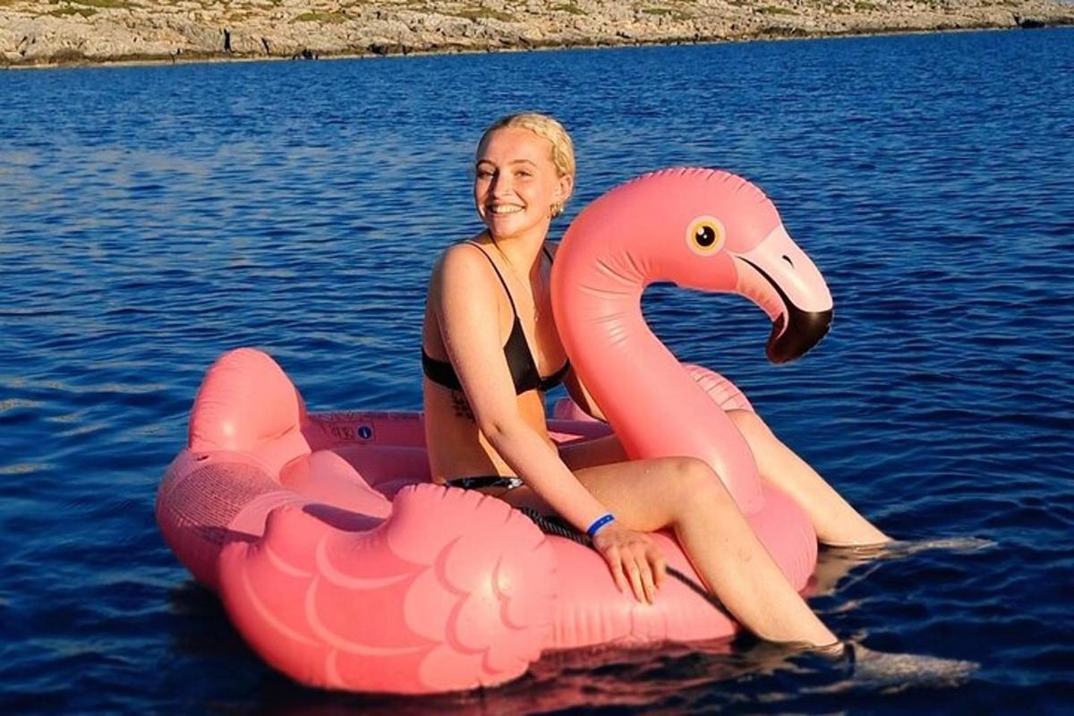 en kvinne som sitter på en rosa flamingo-flåte i vannet