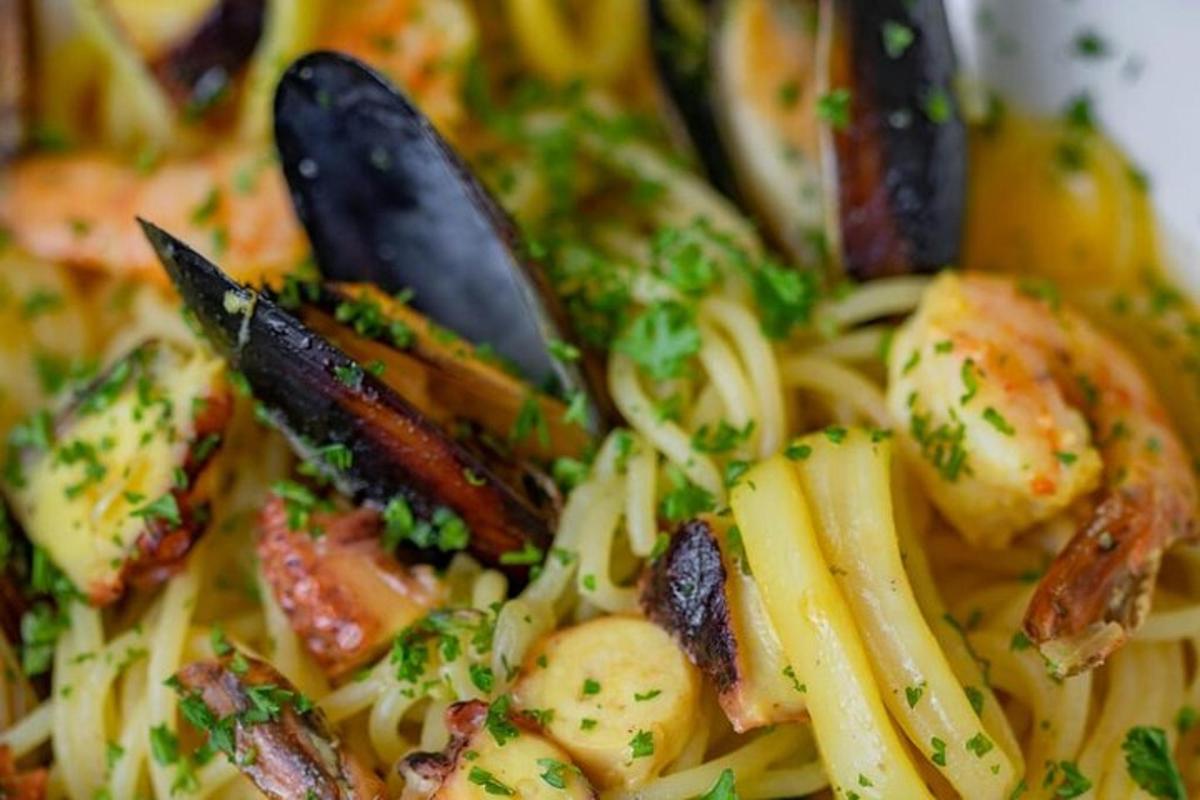 uma tigela de macarrão com camarão e outros vegetais