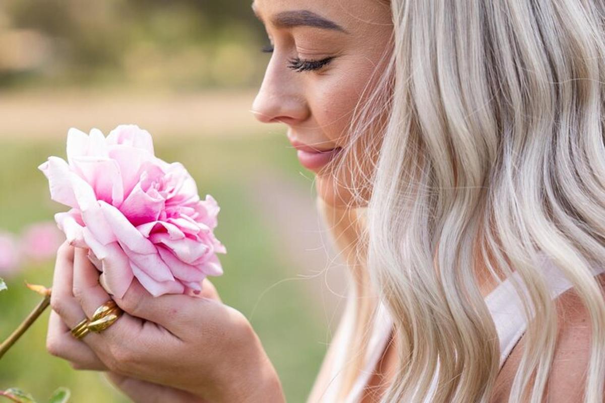 una donna che tiene un fiore rosa tra le mani