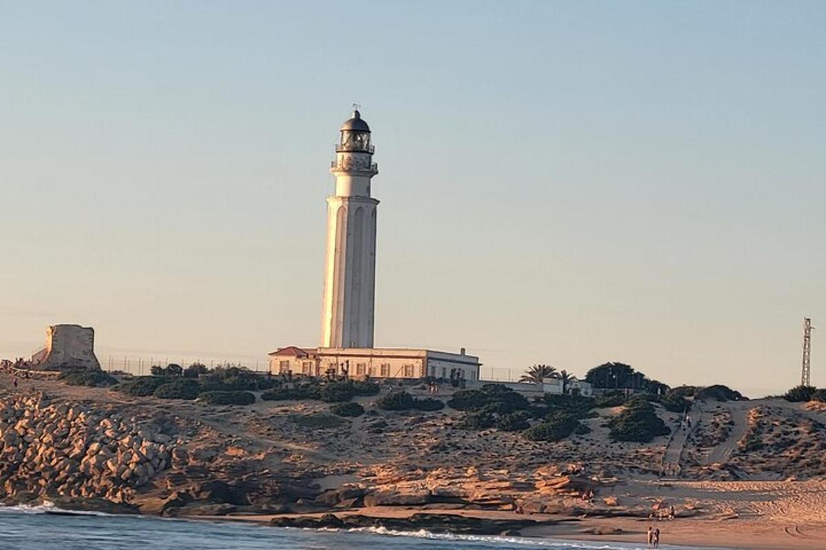 a lighthouse sitting on top of a hill next to the water