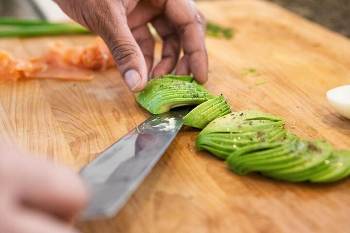 isang taong naghihiwa ng kintsay sa isang cutting board gamit ang isang kutsilyo