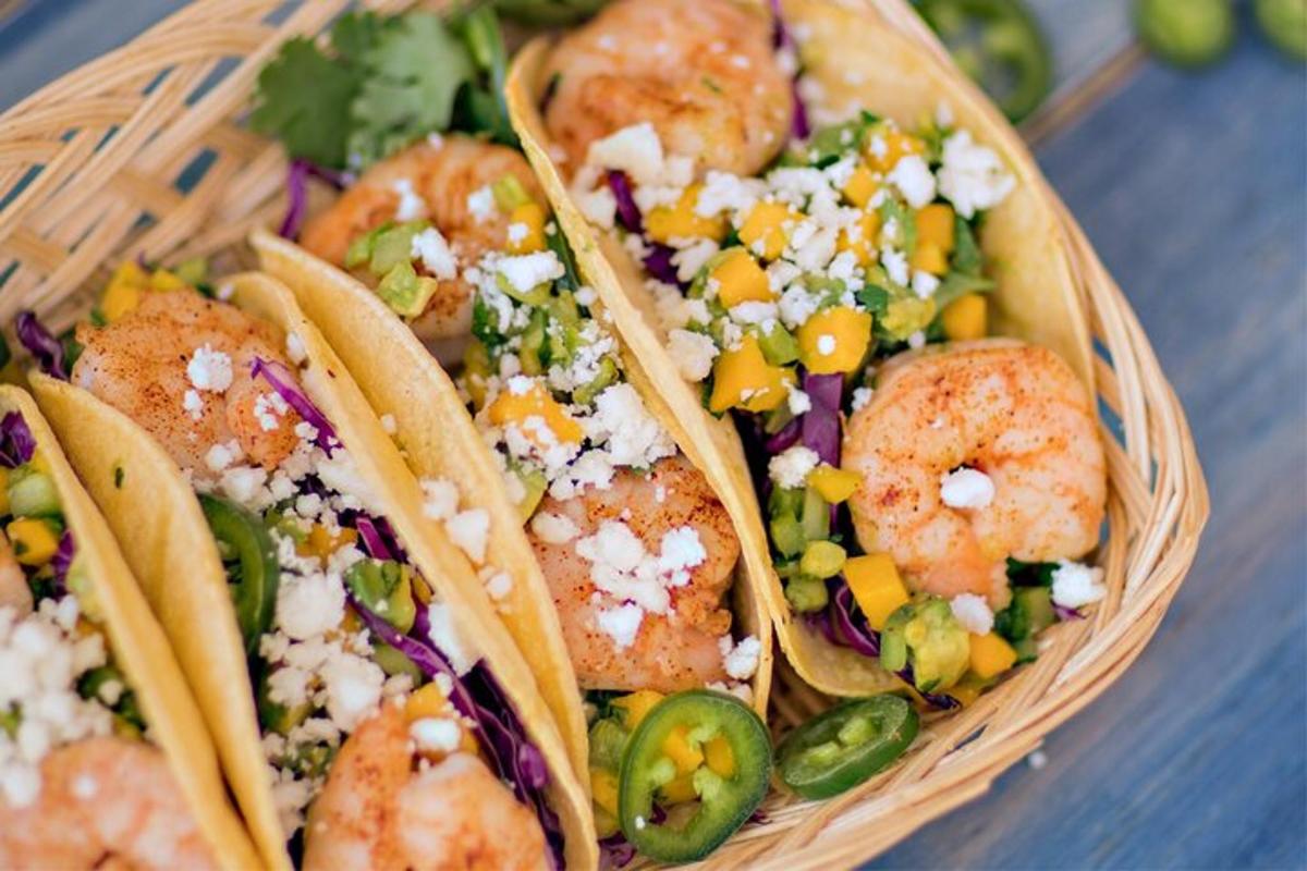 una canasta llena de tacos con camarones y verduras