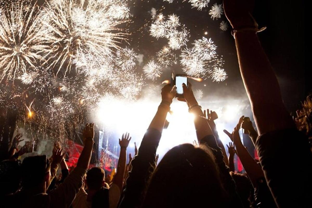 a crowd of people at a concert taking pictures of fireworks