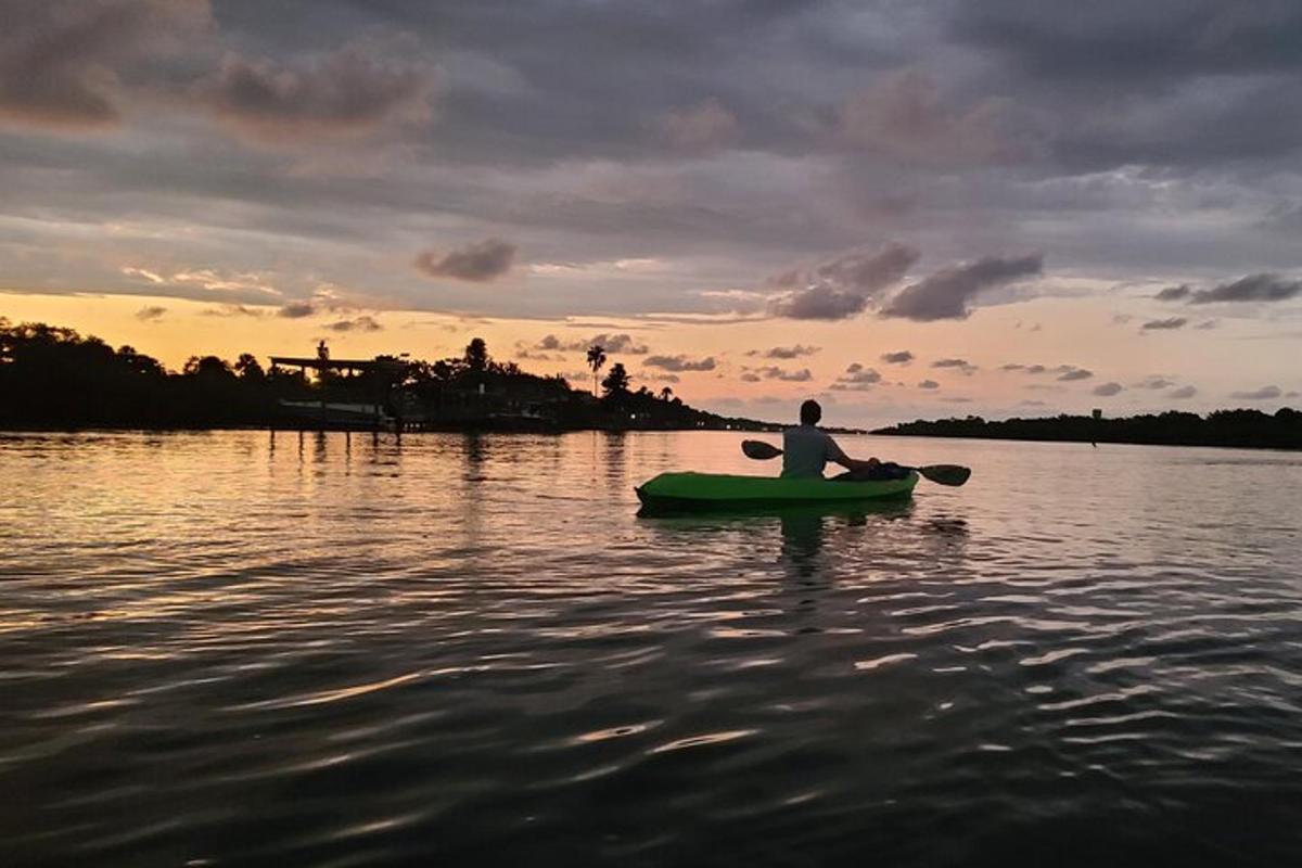 a man in a kayak on the water at sunset