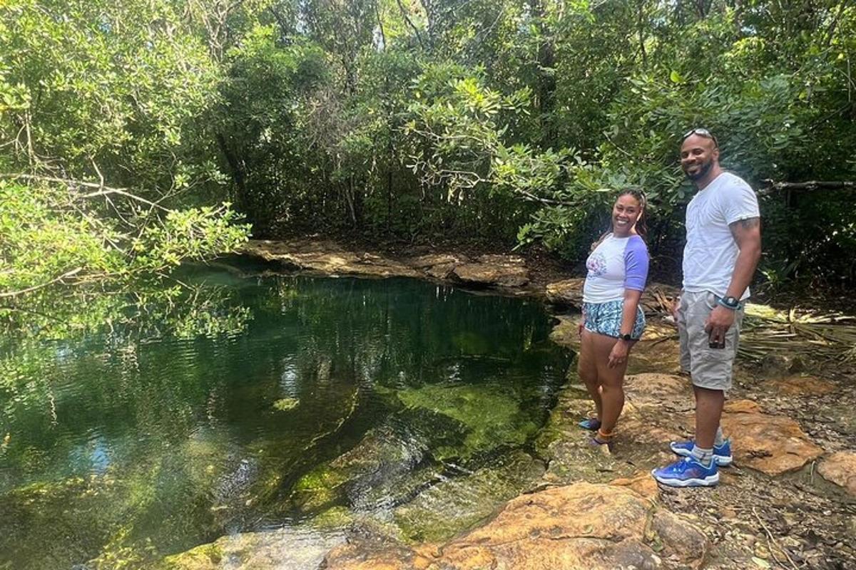 um homem e uma mulher em pé sobre rochas perto de uma poça d'água