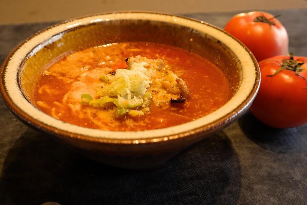 eine Schüssel Suppe mit Tomaten auf einem Tisch
