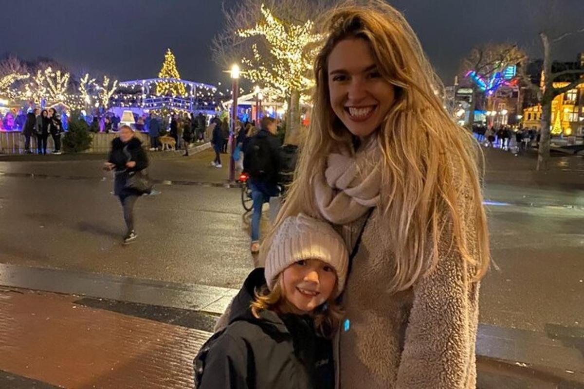 una donna e un bambino in piedi su una strada con le luci di Natale