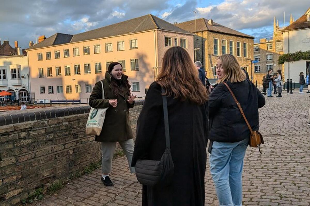 tre kvinner som går nedover en gate nær en mur