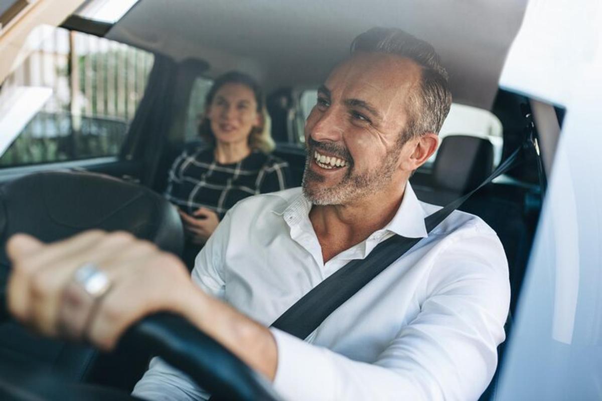 seorang lelaki sedang ketawa sambil duduk di dalam kereta