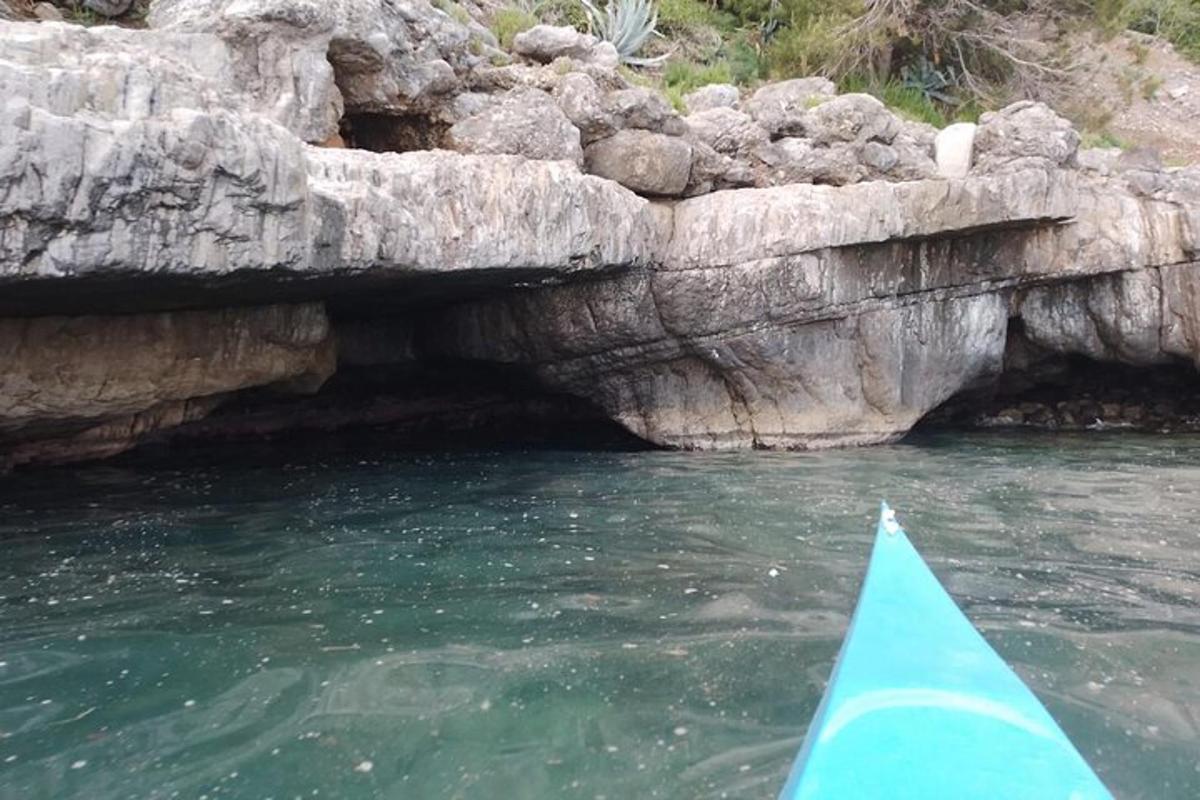 a blue kayak in the water next to a cave