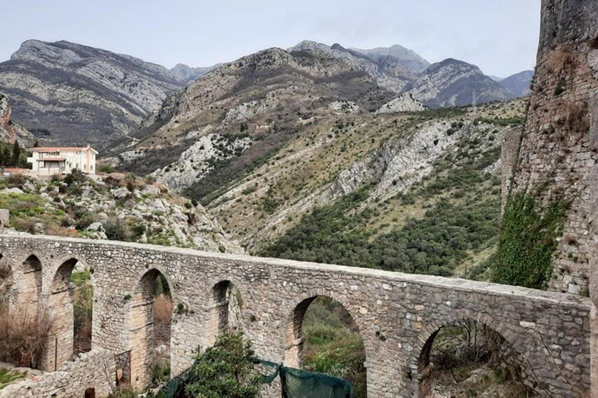 un vecchio ponte di pietra con le montagne sullo sfondo