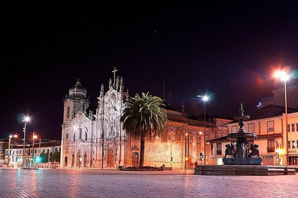 Un gran edificio con una fuente enfrente por la noche.