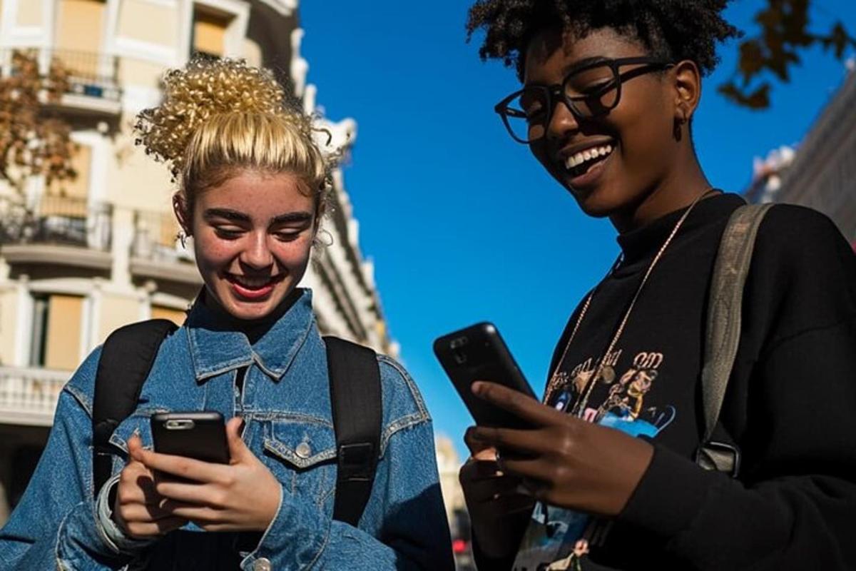 dua orang wanita ketawa sambil melihat telefon bimbit mereka