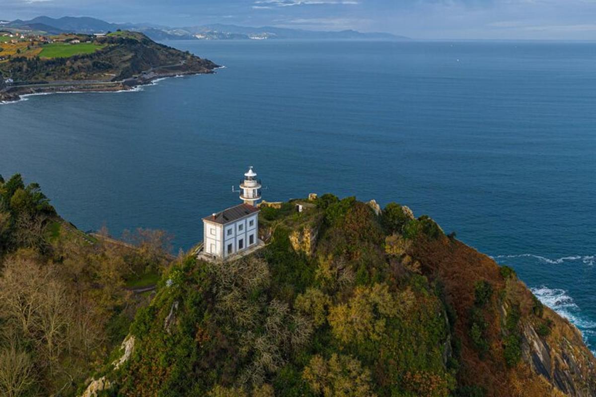 a lighthouse on a hill next to the ocean