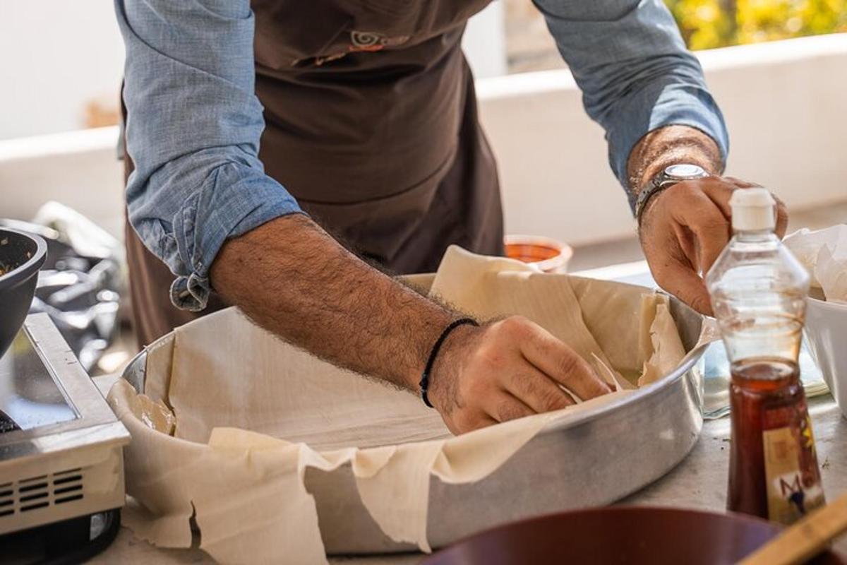 un home preparant menjar en una paella sobre un taulell