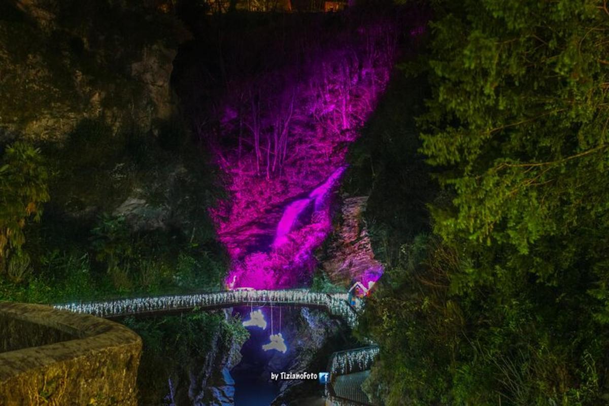un pont sobre un riu amb una cascada porpra