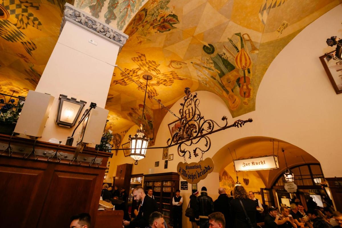 skupina lidí v restauraci se stropem ozdobeným obrazy