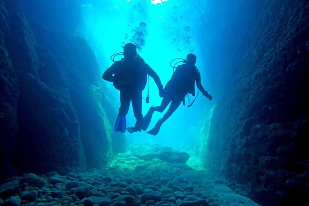 dua orang sedang menyelam di gua biru