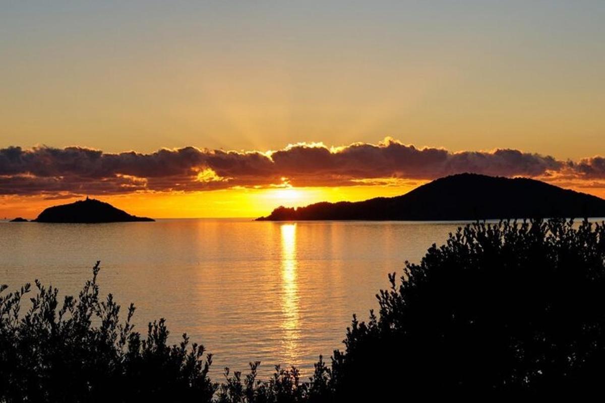 Una puesta de sol sobre un cuerpo de agua con montañas.