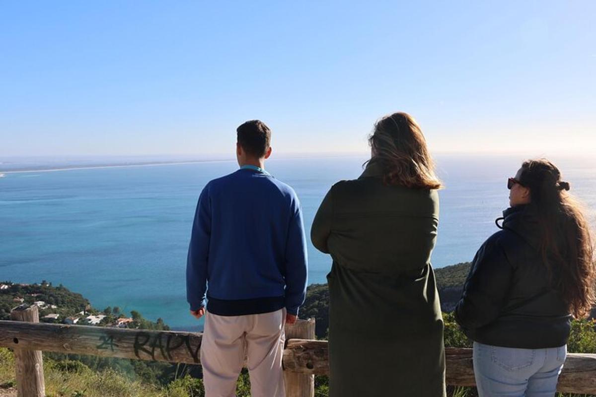 tre persone in piedi su una collina che guardano l'oceano