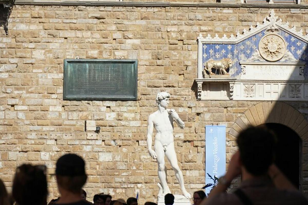 Una estatua de un hombre de pie junto a una pared de ladrillos.