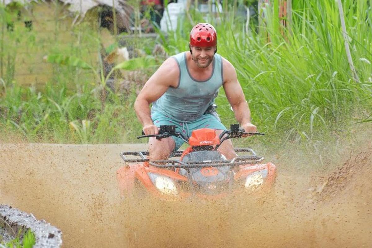 泥の中で四輪バイクに乗る男性