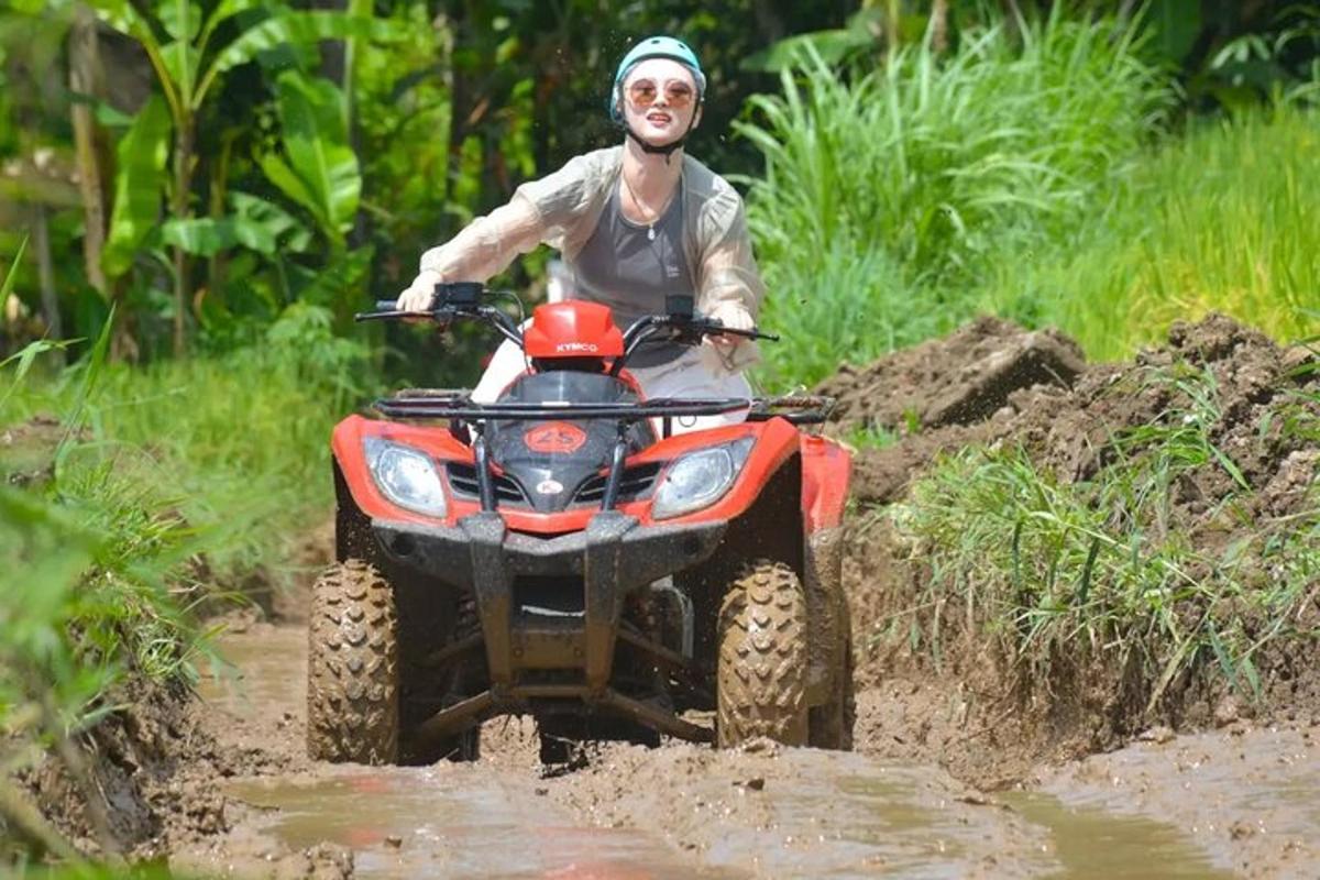isang lalaking nakasakay sa isang four wheeler sa isang lugar na may putik
