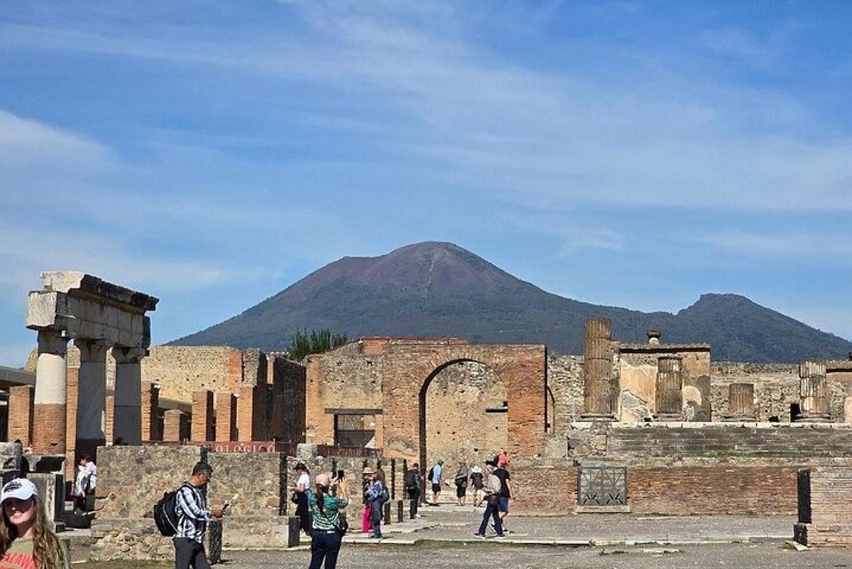 un gruppo di persone che camminano intorno a un antico edificio con una montagna sullo sfondo