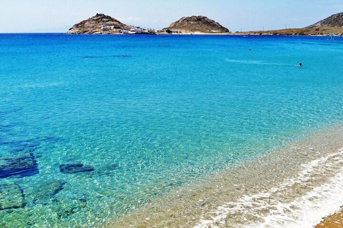 ein Strand mit blauem Wasser und Felsen im Hintergrund