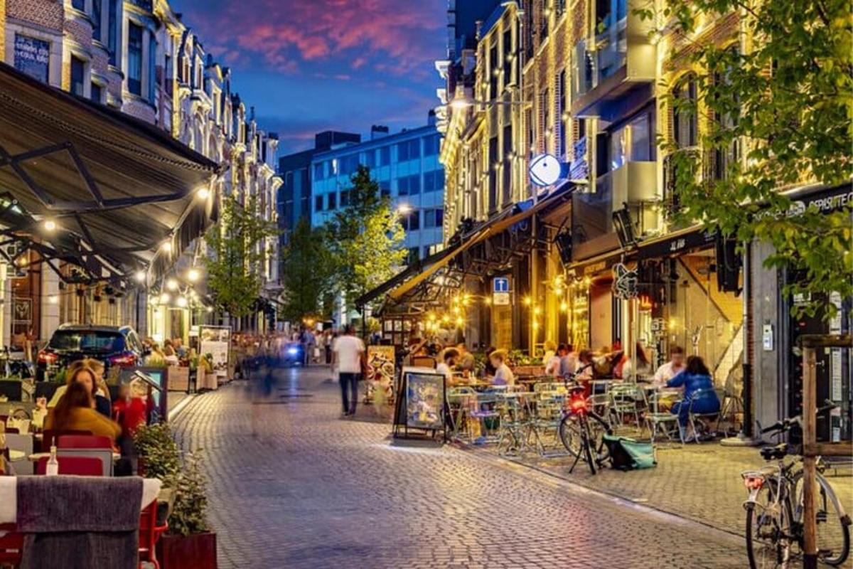 o stradă de oraș noaptea cu oameni așezați la mese