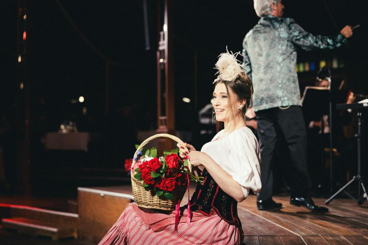 žena sedící na pódiu s košíkem květin