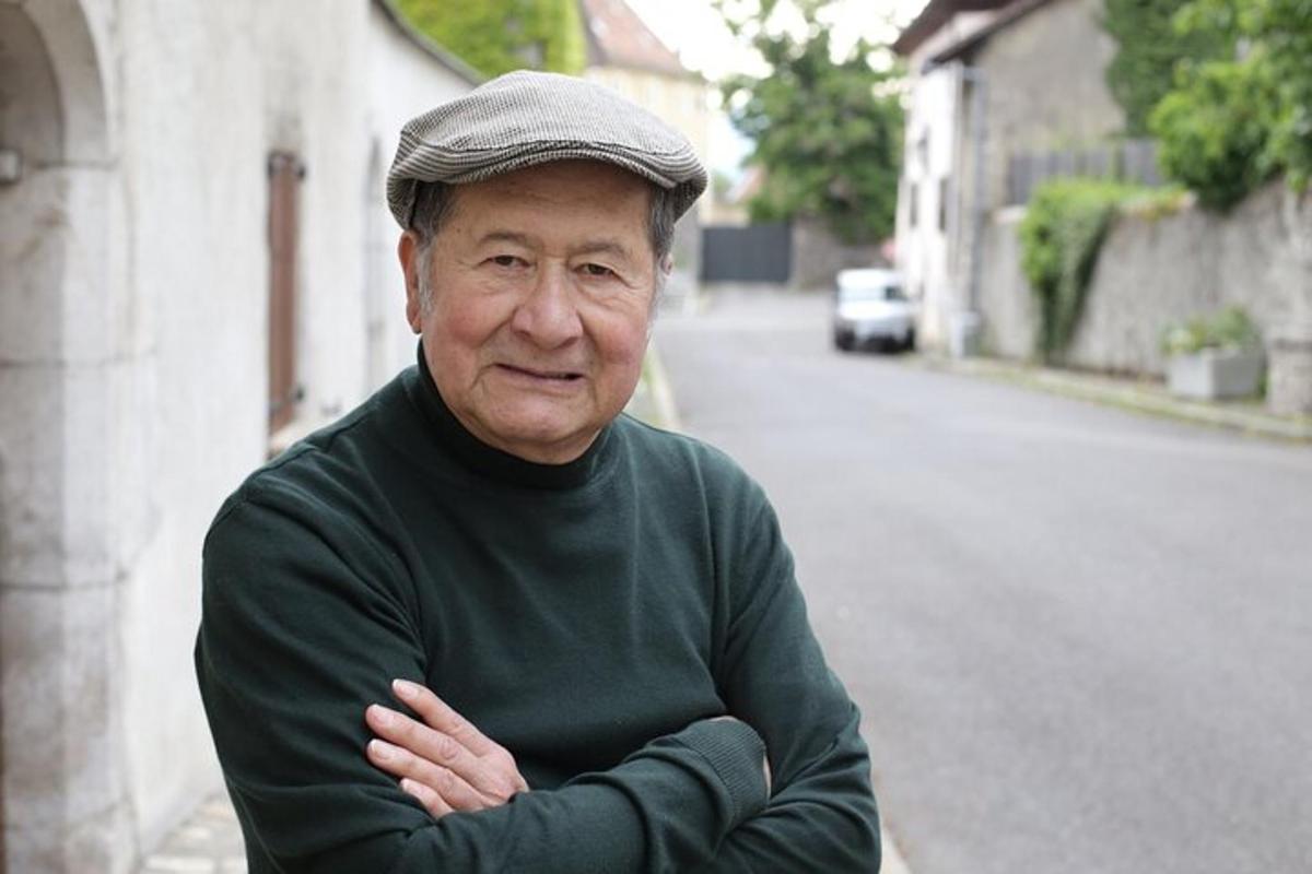 starší muž se zkříženýma rukama stojící na ulici