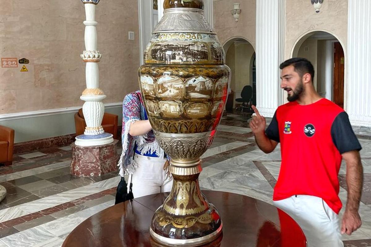 a man is standing next to a large vase