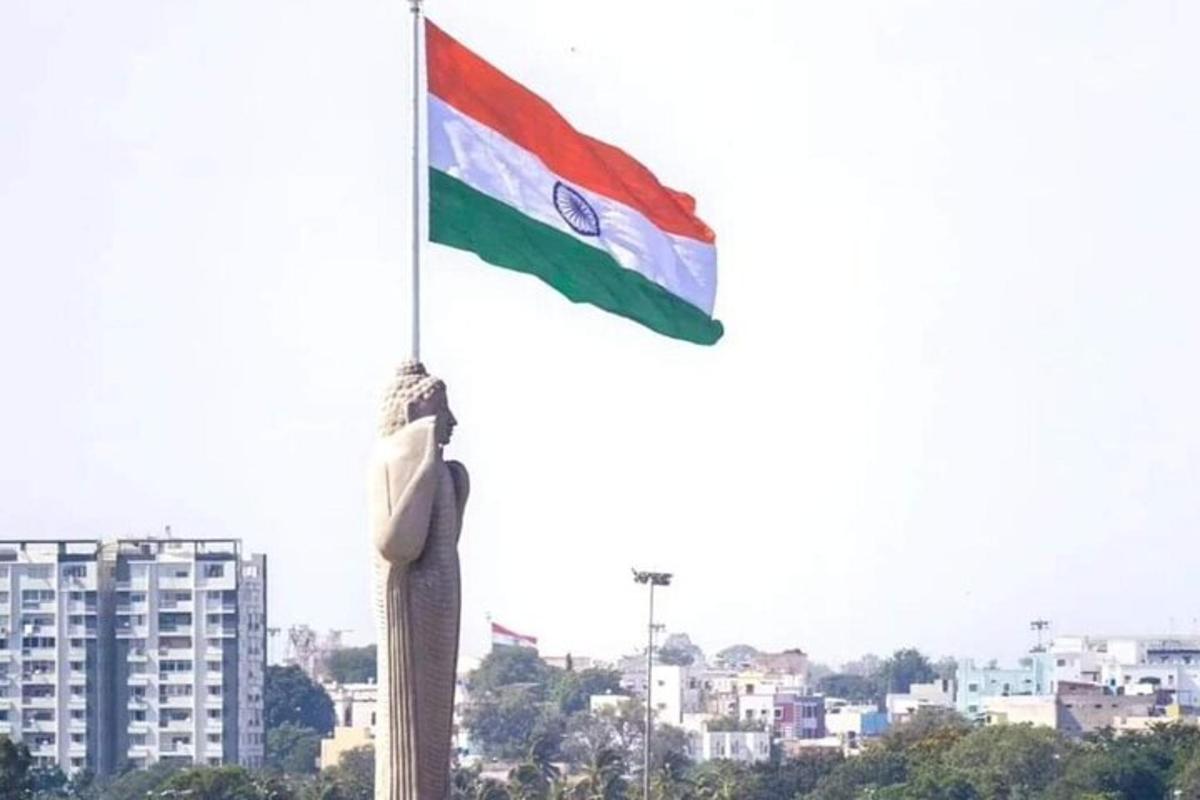 a statue holding a flag in front of a city