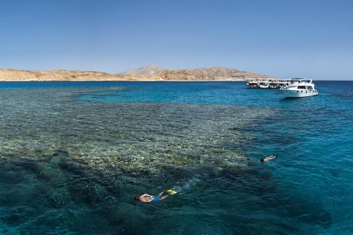 two people swimming in the ocean with a boat