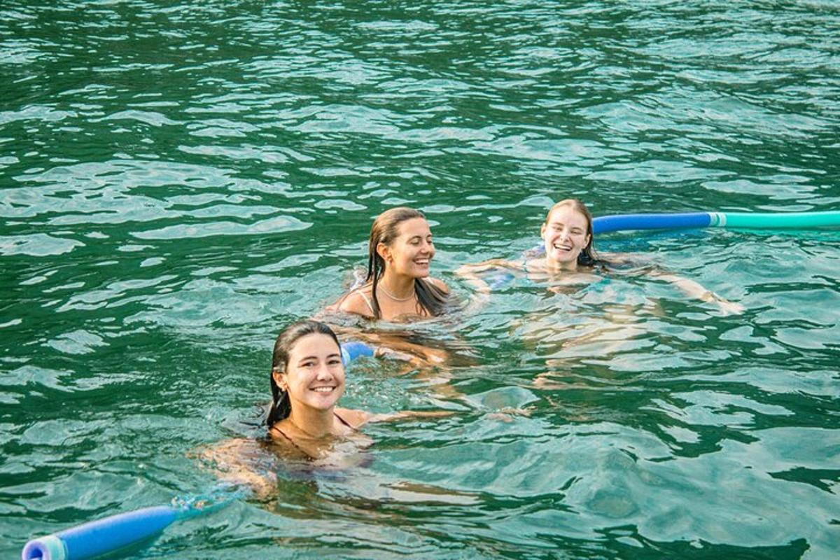 três meninas nadando na água em uma jangada