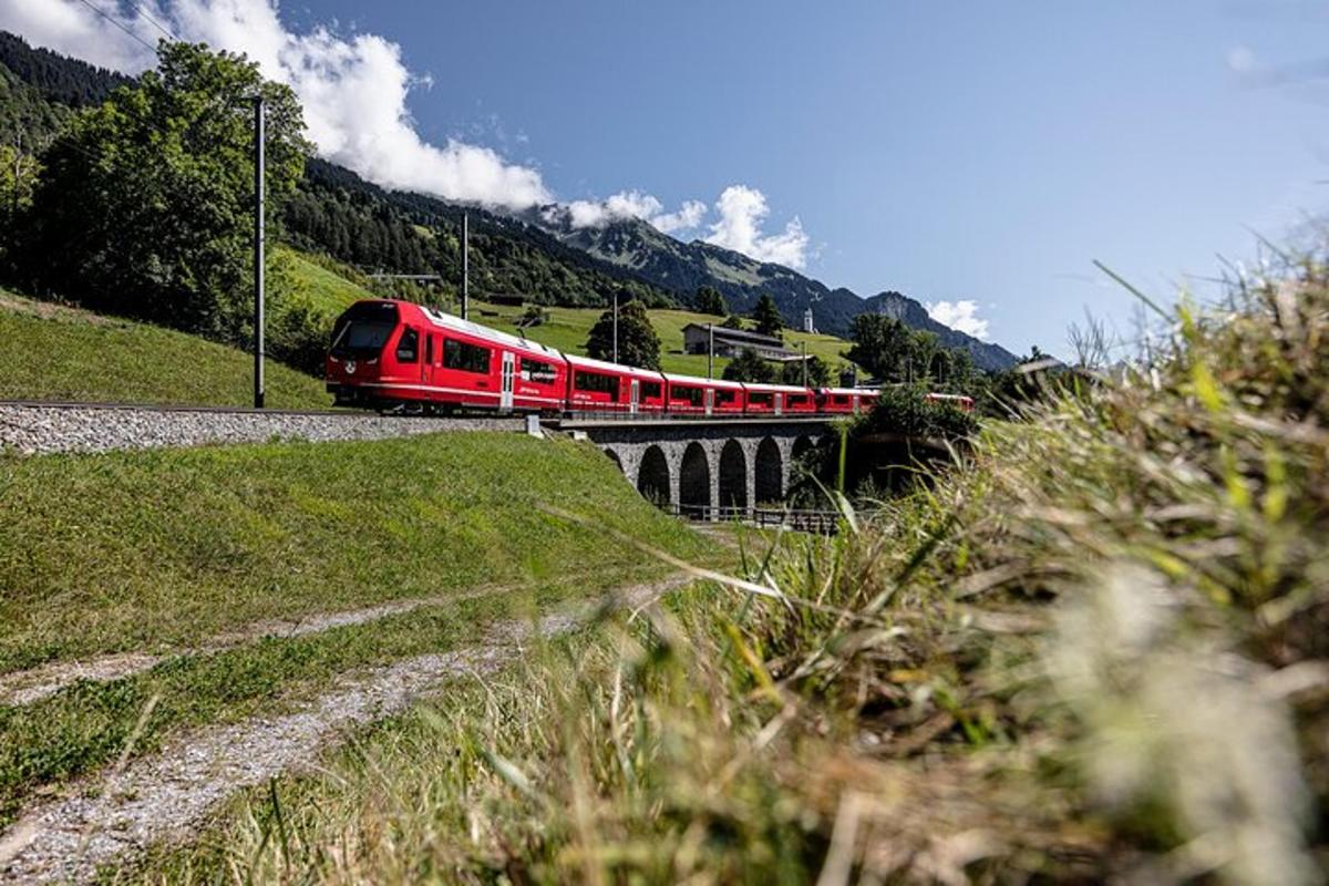 un tren roșu traversând un pod pe o linie