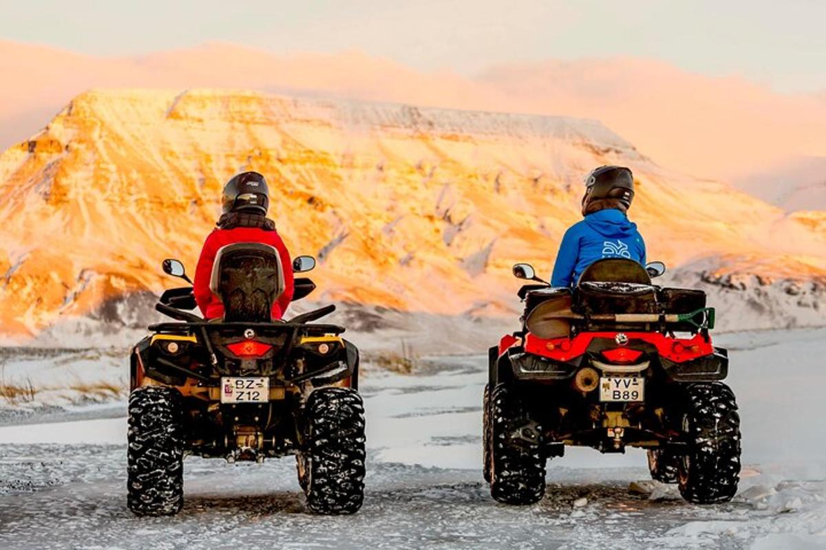 two people are riding atvs on the snow
