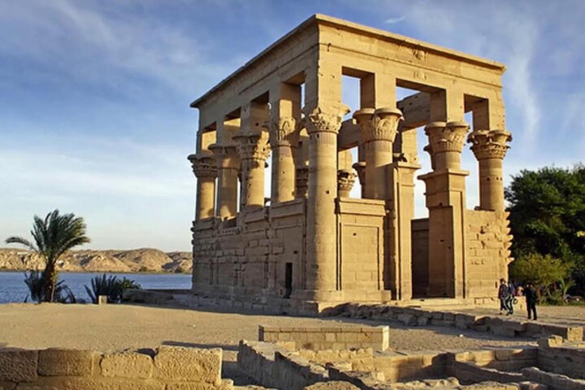a temple with columns next to a body of water