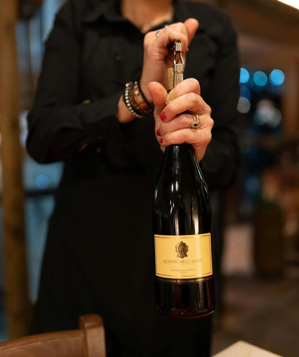 una persona che tiene in mano una bottiglia di vino rosso