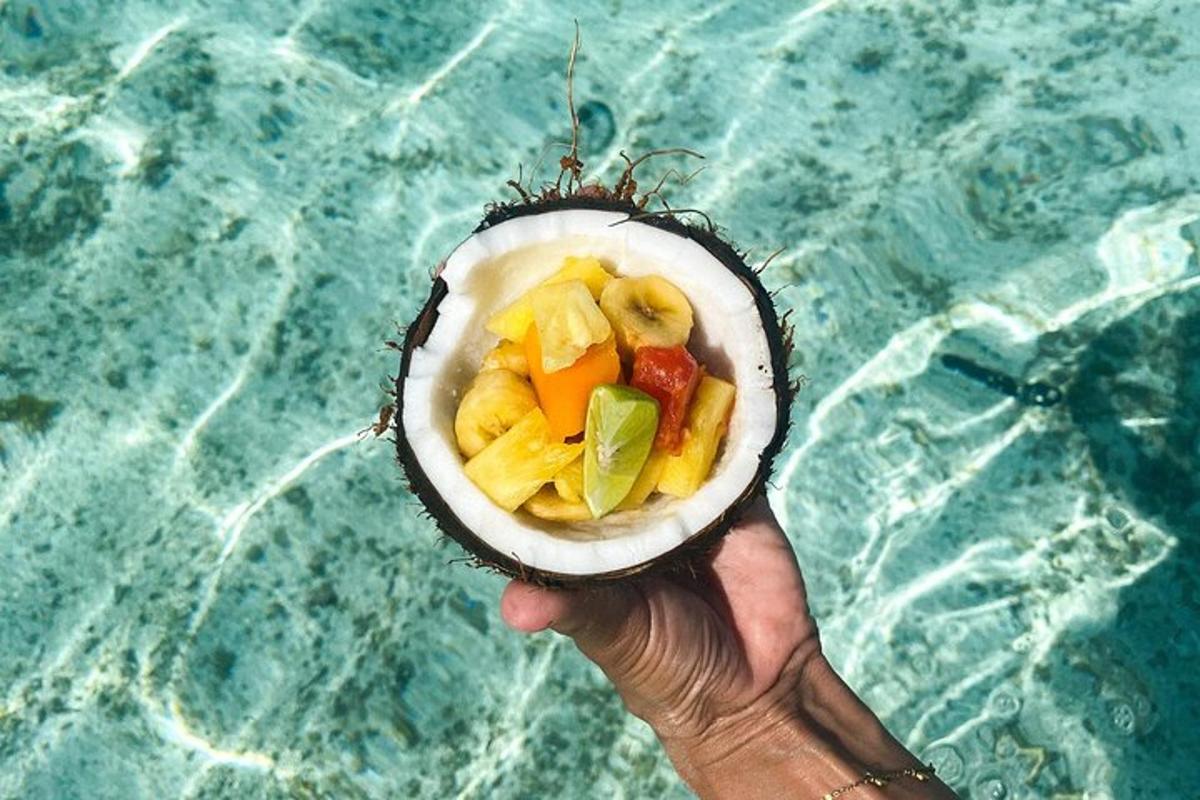 a person holding a bowl of fruit on top of a pool