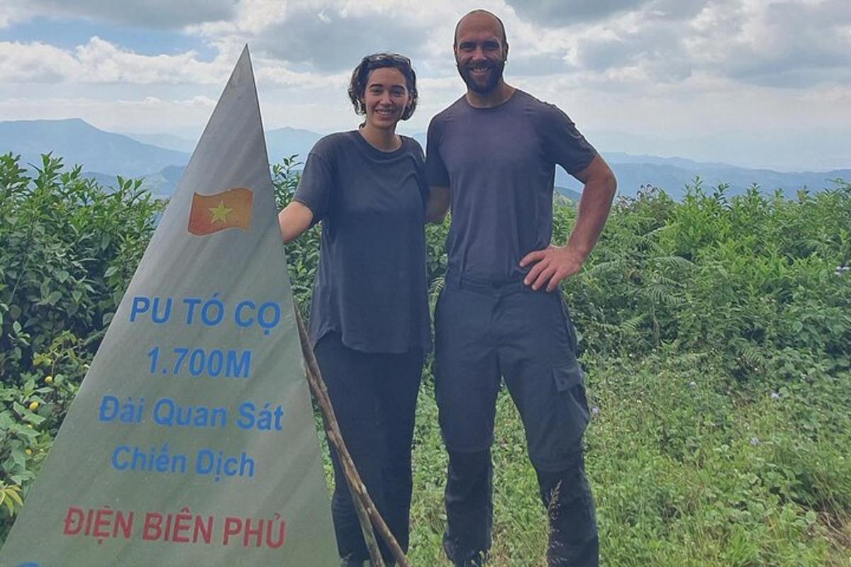 two men standing next to a sign with a surfboard