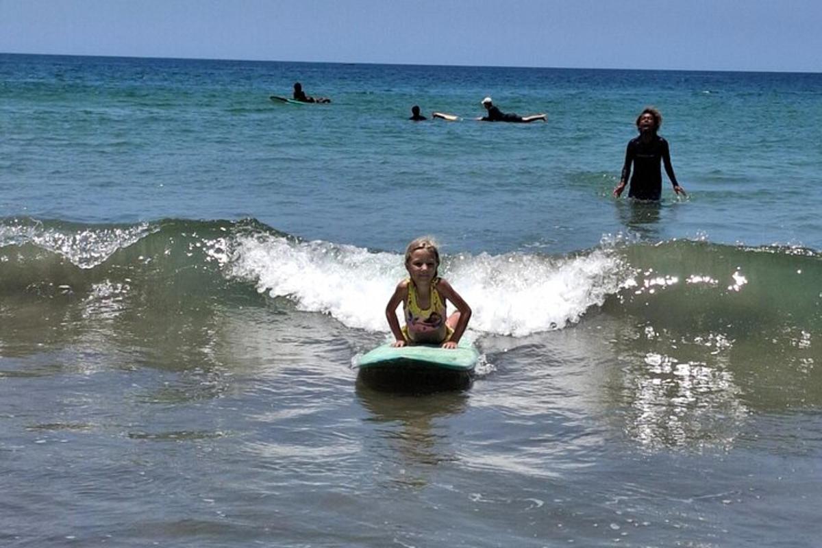 a little girl sitting on a surfboard in the ocean