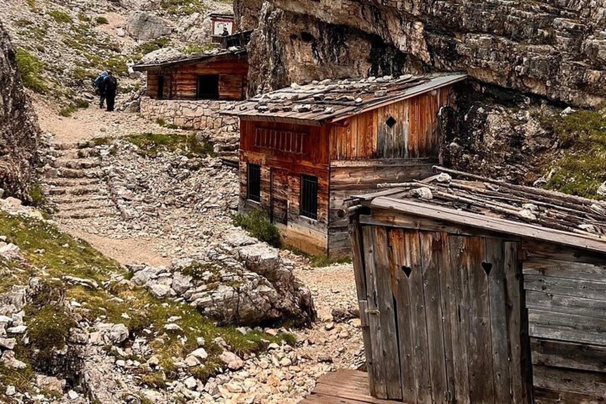 una antiga cabana de fusta a la muntanya amb una persona que hi passa per davant