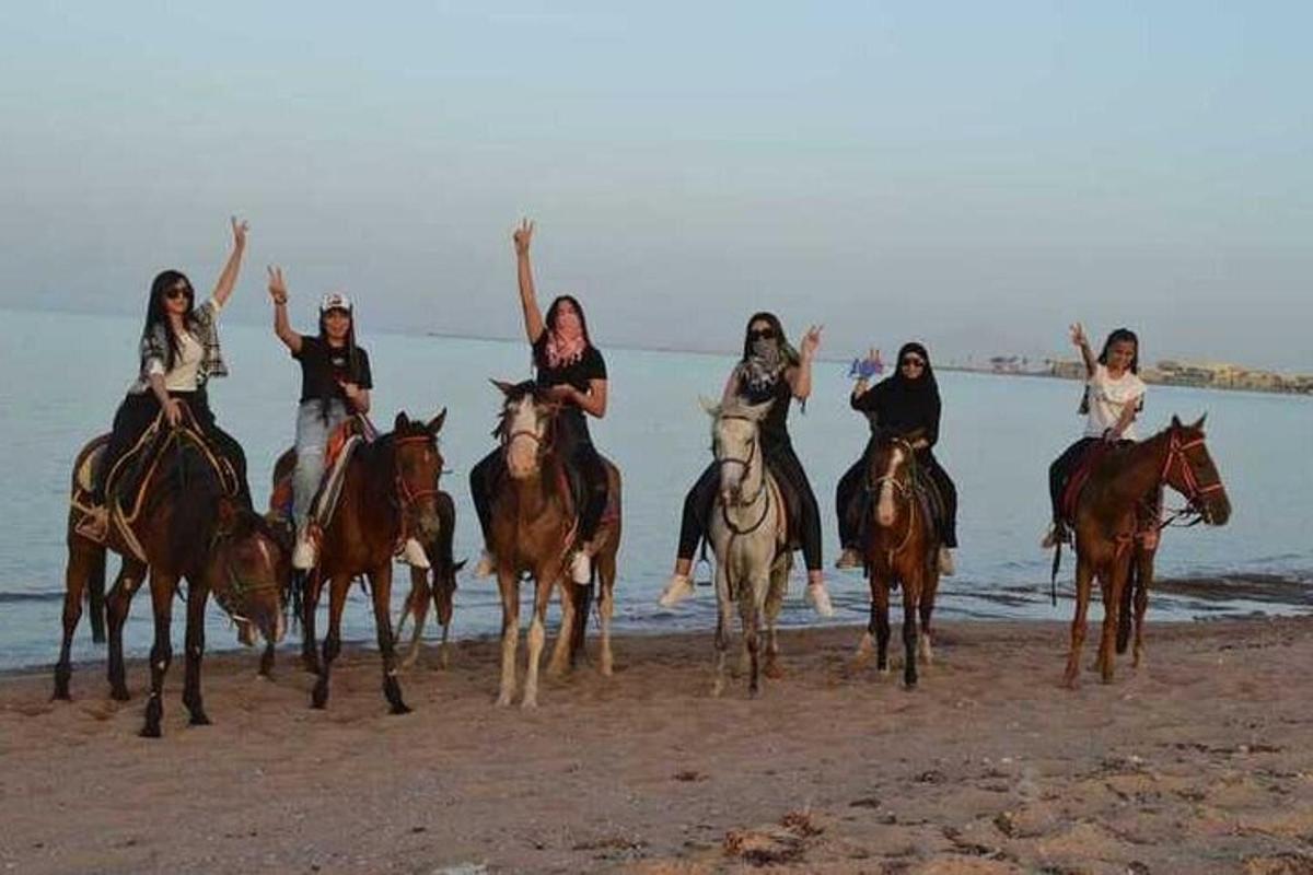 um grupo de pessoas andando a cavalo na praia