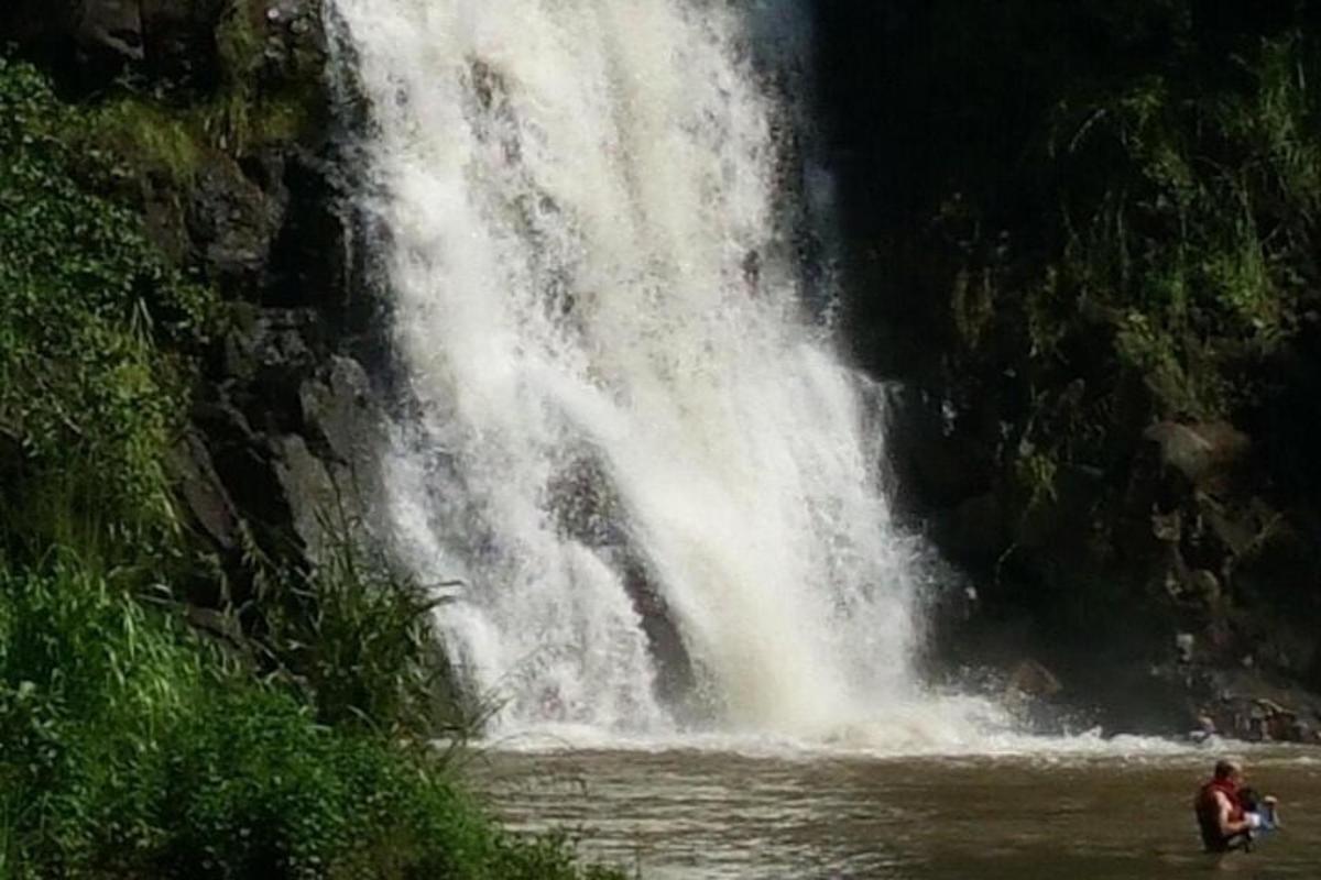 osoba stojící ve vodě před vodopádem