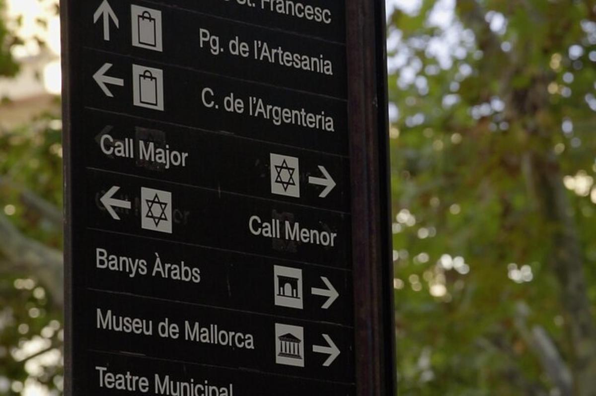 Un cartel negro con flechas en un poste
