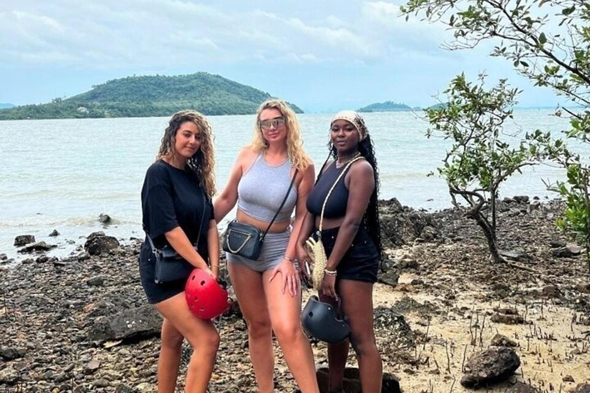Tres mujeres de pie en una playa cerca del agua
