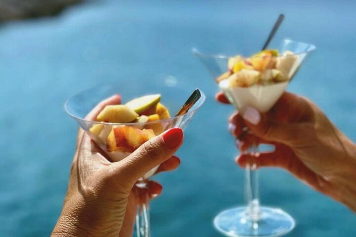 due mani che tengono una ciotola di frutta e un bicchiere di vino