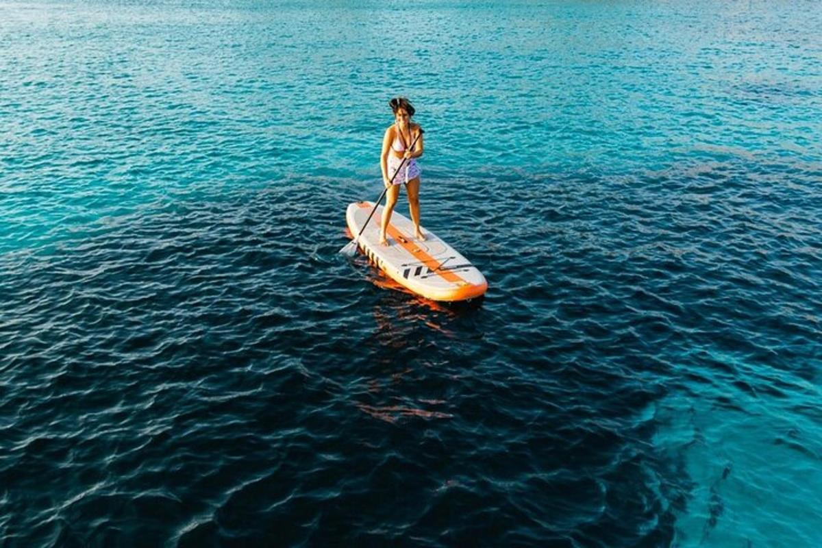 una donna in piedi su una tavola da paddle arancione in acqua